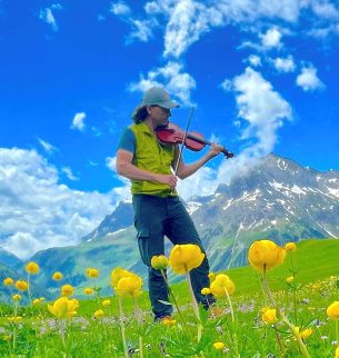 Wanderführer Christian Wirth spielt Violine in einer österreichischen Berglandschaft.