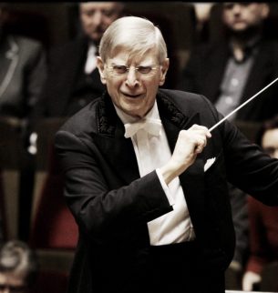 Conductor with baton in front of orchestra