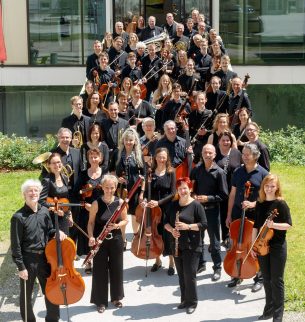 Group photo of an orchestra on a ramp to a house